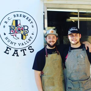 pic of Dave and Joe standing in front of the BCB Eats truck and sign with their arms draped over each other's shoulders