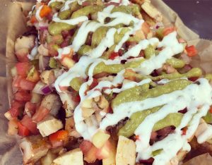 close up picture of loaded PCH fries with sauce, guacamole, chicken, and pico